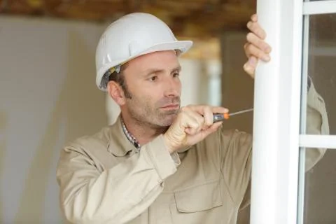 Smiling man is fixing a window handle Stock Photos