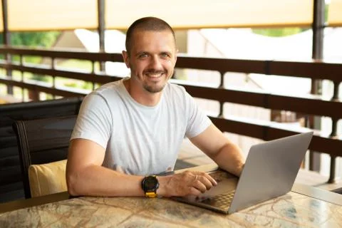 Smiling man freelancer looking in camera and working on laptop. Stock Photos
