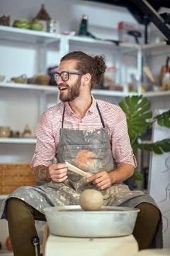 Smiling man in front of wheel  with clay at pottery workshop. Creative, hob.. Stock Photos
