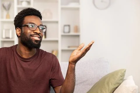 Smiling Man Gesturing While Sitting on a Sofa Indoors Stock Photos