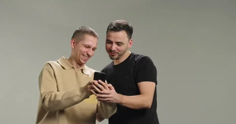 Smiling man gets congratulations isolated on grey background. Male friends using Stock Footage 274225606