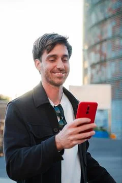 Smiling man happily checking notifications on his smartphone while enjoying a Stock-Fotos
