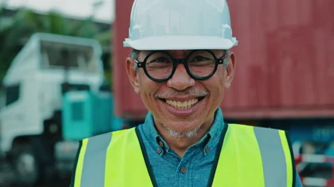 A Smiling Man in a Hard Hat and Safety Vest Stands in Front of a Cargo Container Stock Footage 306185820