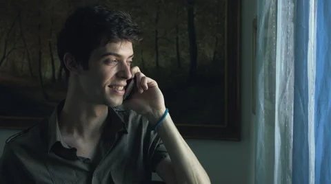 Smiling man having conversation at the phone near the window 库存影片 47827503