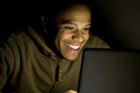 Smiling man on his laptop late at night Stock Photos