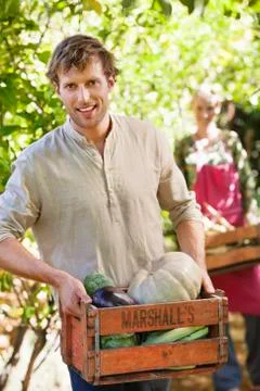 Smiling man holding a crate of vegetables Stock Photos