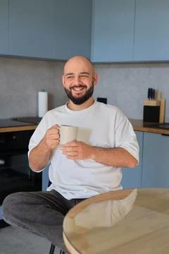 Smiling man holding a cup while sitting at home Stock-Fotos