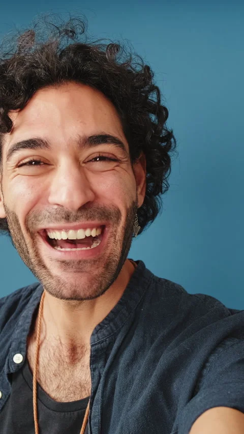 Smiling man looking at camera making video call, welcome sign, isolated on blue Stock Footage 255962616