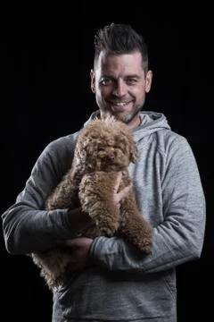Smiling man looking at the camera with a small red poodle dog Stock Photos