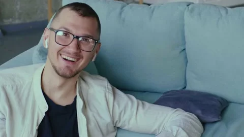 Smiling man is looking at camera through glasses while working from home Stock Footage 155372589