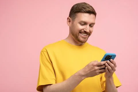 Smiling man looking at smartphone screen, browsing in internet, chatting with Stock Photos