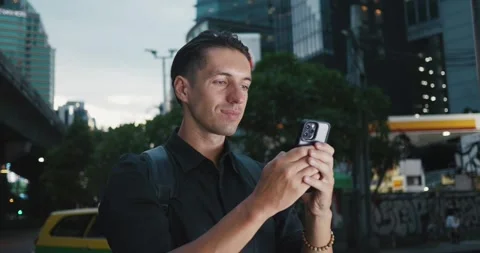 Smiling man in love writes message on his mobile phone to his girlfriend while Stock Footage 250932154
