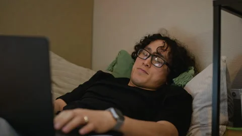 Smiling Man Lying in Bed Typing on Laptop Working Remotely Stock Footage 338421743