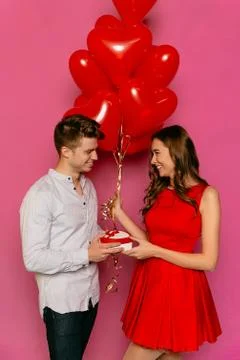 Smiling man making a present for her gorgeous girlfriend on St. Valentine's d Stock Photos
