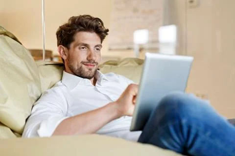 Smiling man in office using tablet in bean bag Stock Photos