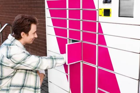 Smiling man opens a contactless parcel locker for an online ecommerce picku.. Foto stock