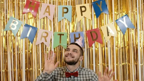 Smiling man in a party hat and red bow tie dancing and waves his hands under Stock Footage 342620667