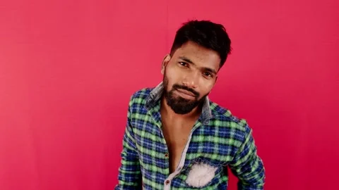 Smiling man in plaid shirt posing against a vibrant red background side vie.. Stock Footage 262366410