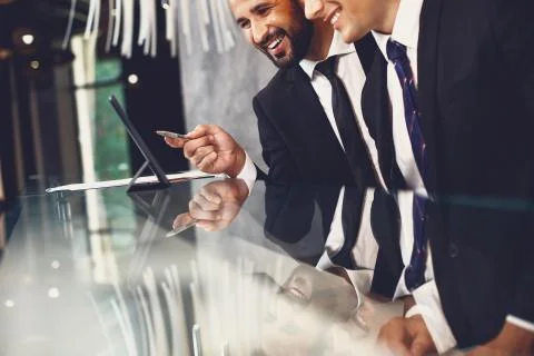 Smiling man pointing to the screen of modern tablet while being with colleague Stock Photos