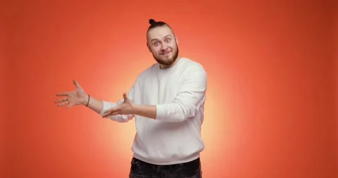 Smiling man points hands aside pretends he gives something on red background. Video stock 148994993