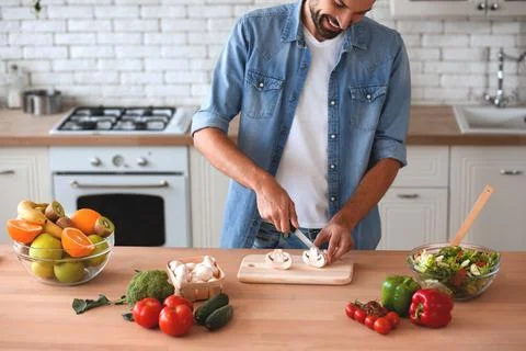 Smiling man preparing salad at the kitchen Stock Photos