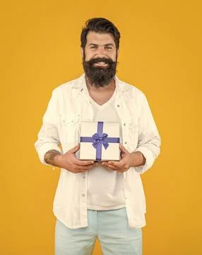 Smiling man with present box isolated on yellow. man with present box in studio. Stock Photos