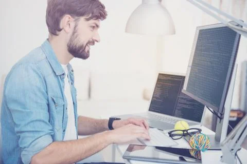 Smiling man programming in a cozy office Stock Photos