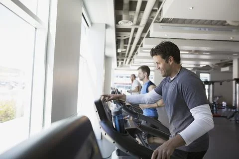 Smiling man programming treadmill at gym 스톡 사진