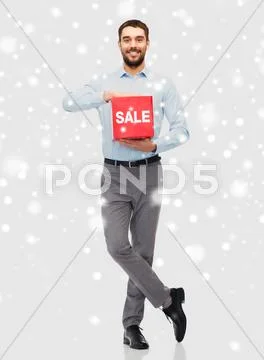 Smiling man with red sale sign over snow Stock Photos