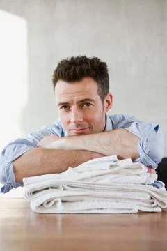 A smiling man resting on a stack of folded laundry Stock Photos