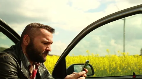 Smiling man sends sms, sitting in car Stock Footage 62861412