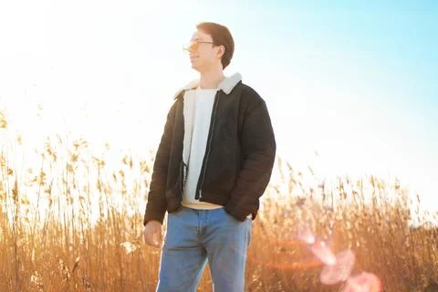 A smiling man in a shearling jacket and sunglasses enjoys the warm sun and .. Stock Photos