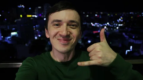 Smiling man showing call me hand gesture at night Stock Footage 344283945