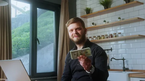 Smiling man showing a stack of hundred-dollar bills while sitting in a mode.. Stock Footage 310860085