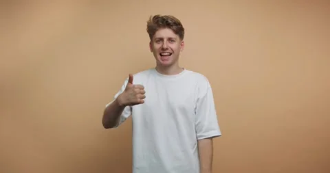 Smiling man showing thumbs up in different frames indoors with plain backgrou 動画素材 328247163