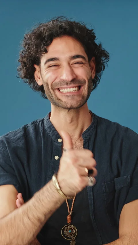 Smiling man showing thumbs up looking at camera isolated on blue background in Stock Footage 254912990