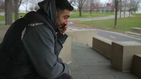 Smiling Man is sitting on the bench talking on the phone and looking at the sea Stock-Footage 82652622