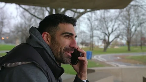 Smiling Man is sitting on the bench talking on the phone and looking at the sea Vidéo 82653045