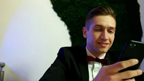 Smiling man sitting at table and using smartphone Stock Footage 75809277