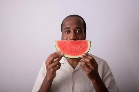 Smiling man with a slice of watermelon in front of his mouth as a sign of s.. Stock Photos