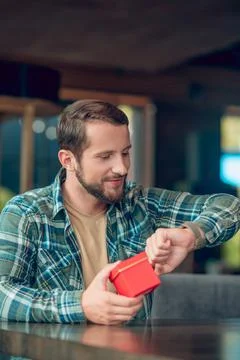Smiling man with small box looking at hand Stock Photos