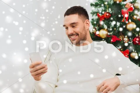 Smiling man with smartphone at home for christmas Stock Photos
