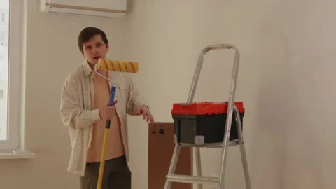 Smiling man standing with toolbox, step ladder, and paint tools Vidéo 346159499
