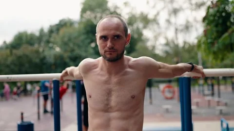 Smiling Man Stretches on Parallel Bars at Outdoor Gym Stock Footage 307409203