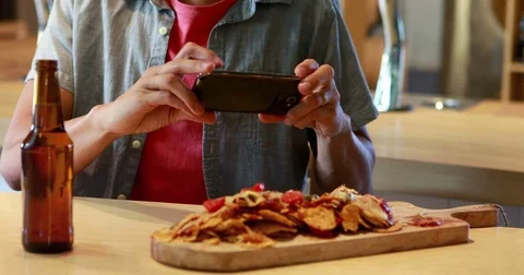 Smiling man taking a picture of food on his mobile phone 4k Stock Footage