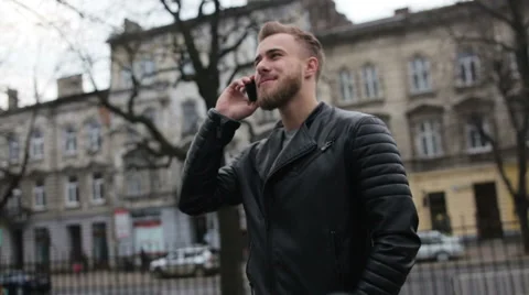 Smiling man talking on his phone while standing in the street Stock Footage 63468276