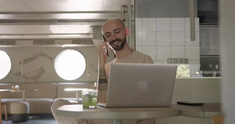 Smiling man talking on mobile and using laptop at cafe Stock Footage 159082948