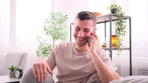 Smiling man talking mobile phone in living room Stock Footage 171542778