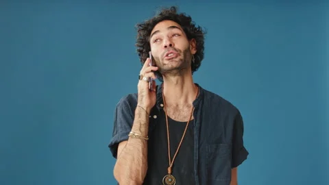 Smiling man talking on mobile phone isolated on blue background in studio Stock Footage 255963032