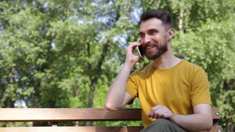 Smiling man talking on smartphone on bench in park Stock-Footage 136115384